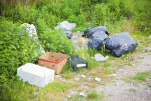 A pile of trash that was illegally dumped on the side of the road.